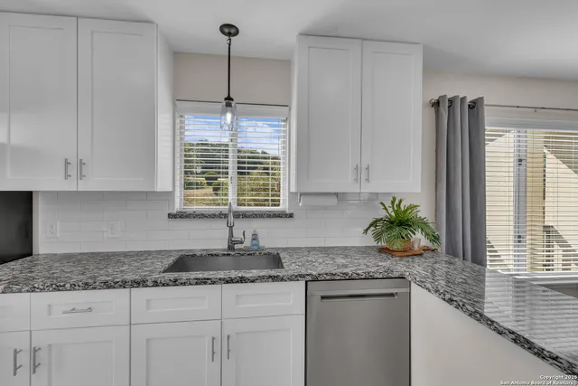 a kitchen with granite countertop white cabinets and a window