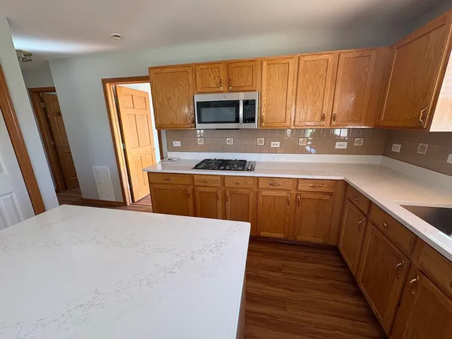 a kitchen with stainless steel appliances a sink a stove top oven a refrigerator and dishwasher with wooden floor