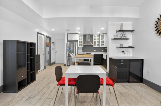 a large kitchen with stainless steel appliances kitchen island granite countertop a refrigerator a sink dishwasher a dining table and chairs with wooden floor