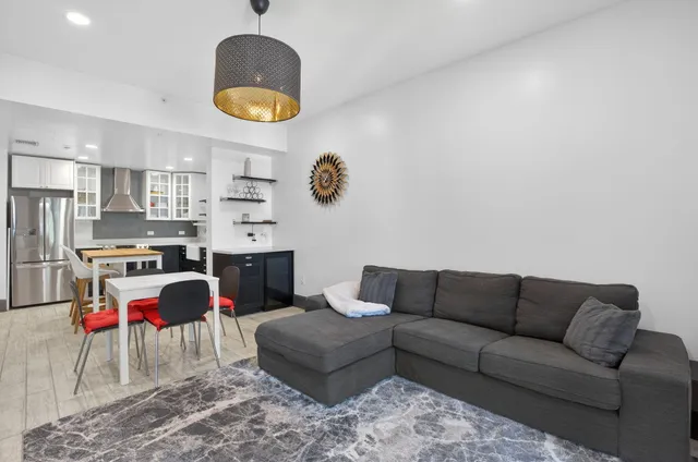a living room with stainless steel appliances kitchen island a table and a couch