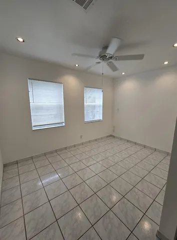 an empty room with windows and ceiling fan