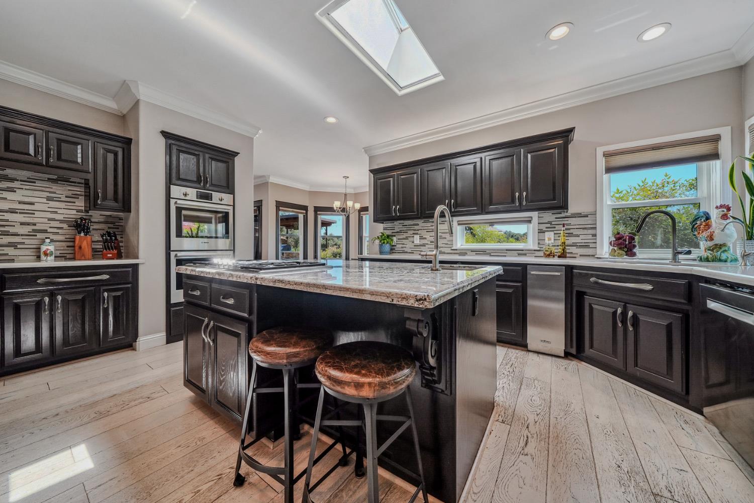10786 Shenandoah Road Plymouth, CA 95669 - Photo 20 of 99 a kitchen with stainless steel appliances granite countertop a stove top oven a sink dishwasher a dining table and chairs with wooden floor