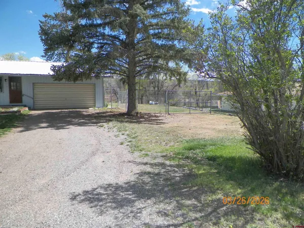 a backyard of a house with large trees and a barn