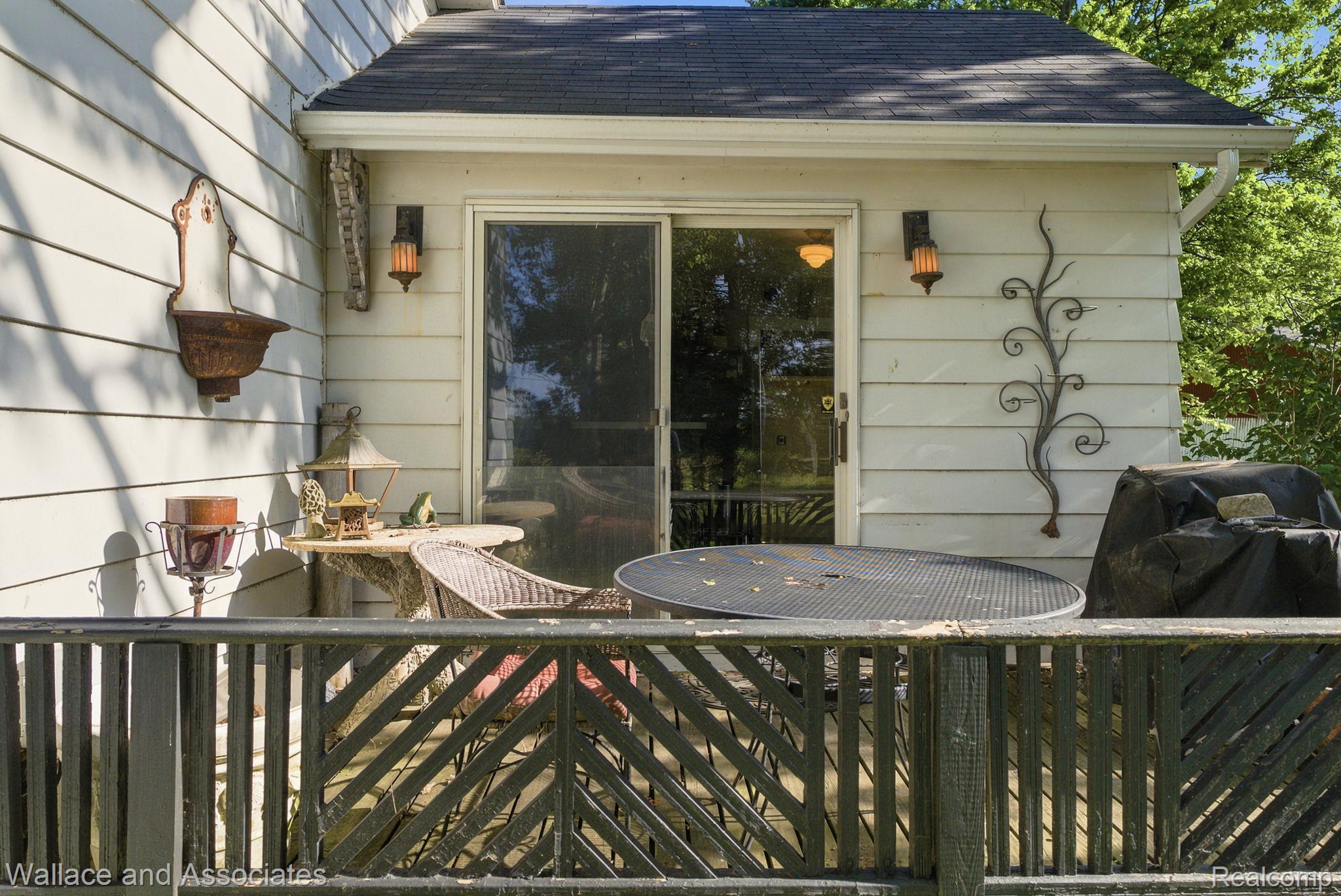 5949 Roach Road Croswell, MI 48422 - Photo 10 of 48 Outdoor deck area featuring a sliding glass door entry to the interior, exterior wall sconces, and a dark shingle roofline