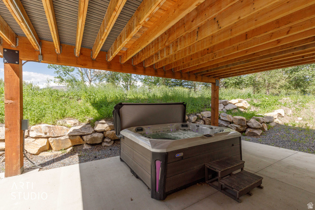1188 South Old Trappers Loop Road Huntsville, UT 84317 - Photo 73 of 92 Outdoor spa area featuring a bubbling hot tub with wooden steps, set on a concrete patio under a wooden deck with a corrugated metal ceiling