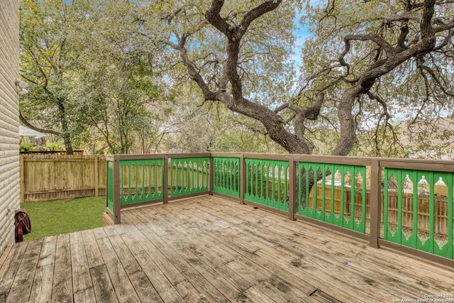 a view of a backyard with large trees and wooden fence