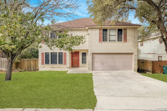 a front view of a house with a garden and trees