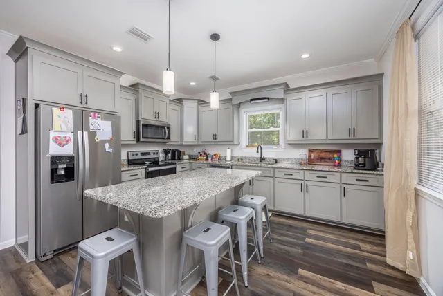 a kitchen with stainless steel appliances granite countertop a sink a stove a refrigerator cabinets and chairs