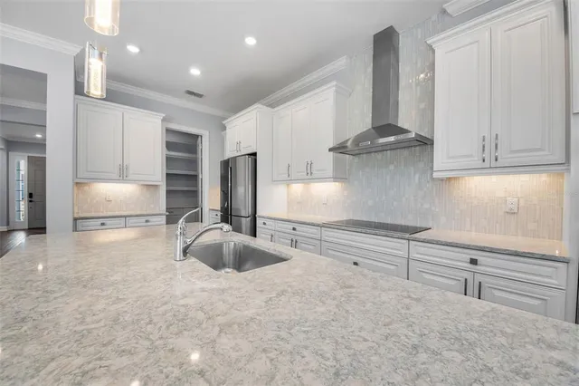 a large kitchen with kitchen island granite countertop a large window and white cabinets