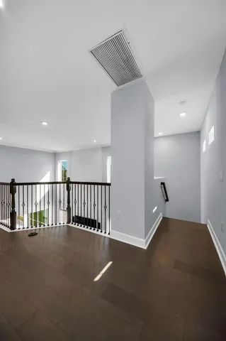 a view of an empty room with wooden floor and staircase