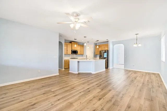 an empty room with wooden floor fan and windows