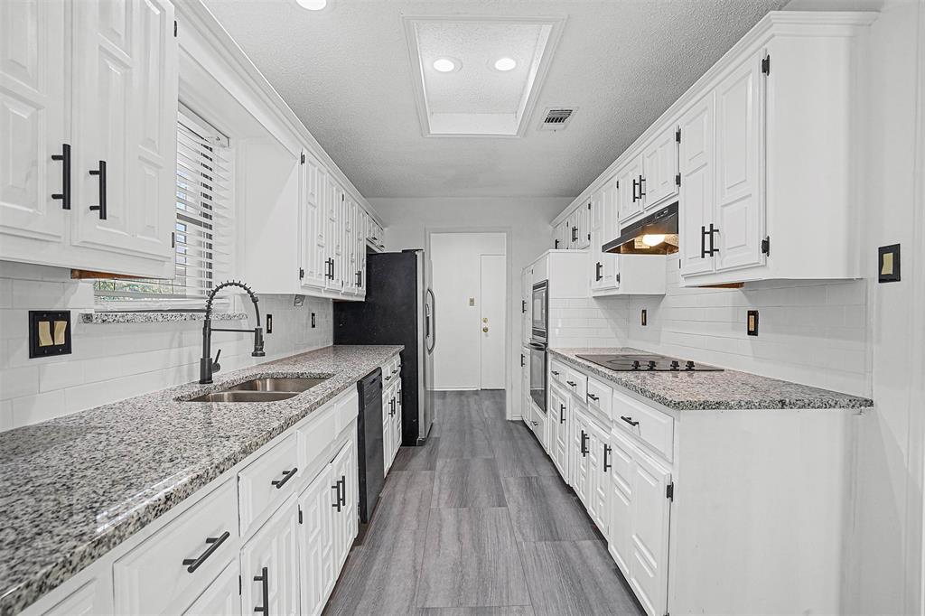 a kitchen with granite countertop a sink stove refrigerator and cabinets