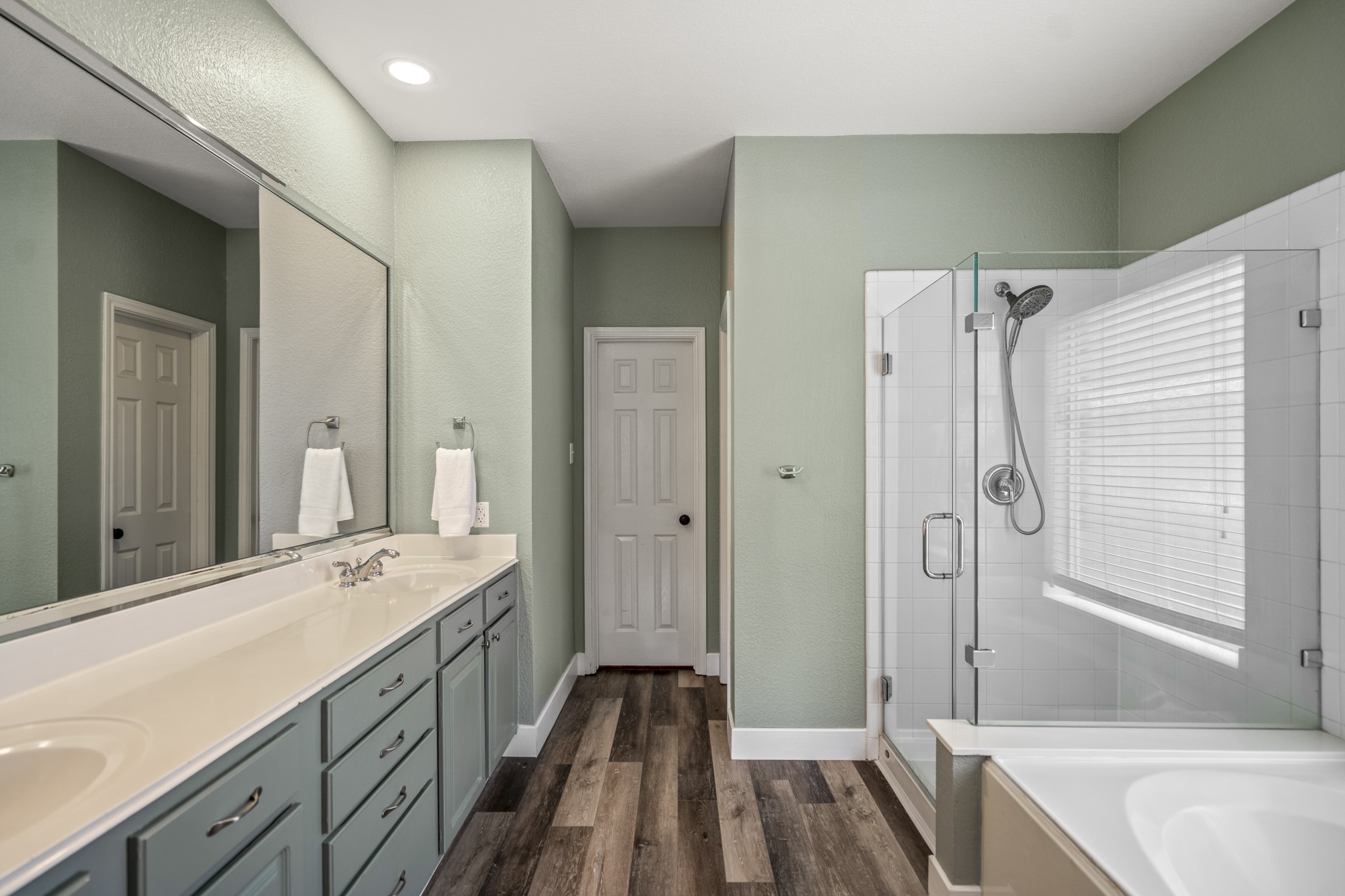 5835 Pinelake Crossing Drive Spring, TX 77379 - Photo 19 of 50 The primary bath offers a clean, spacious layout with an extended double vanity and generous drawer storage, making busy mornings feel a little more effortless. Updated LVP flooring runs underfoot, while the glass-enclosed shower and soaking tub create a space to either get ready for the day or slow down and unwind, with natural light keeping everything bright and easy.