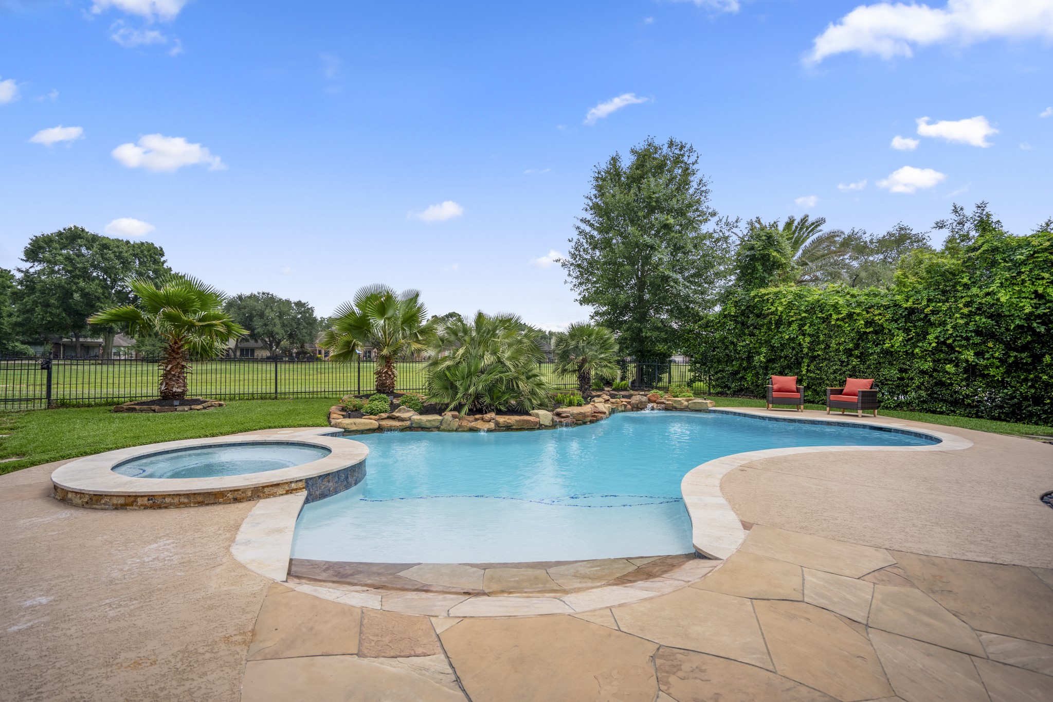 5835 Pinelake Crossing Drive Spring, TX 77379 - Photo 33 of 50 Stepping outside, the backyard opens up to a resort-style setting with a sparkling pool, raised spa, and a beach entry that makes it easy to ease right in. Natural stone accents and lush landscaping frame the space, while open views to the golf course beyond the fence create a backdrop that feels both private and expansive.