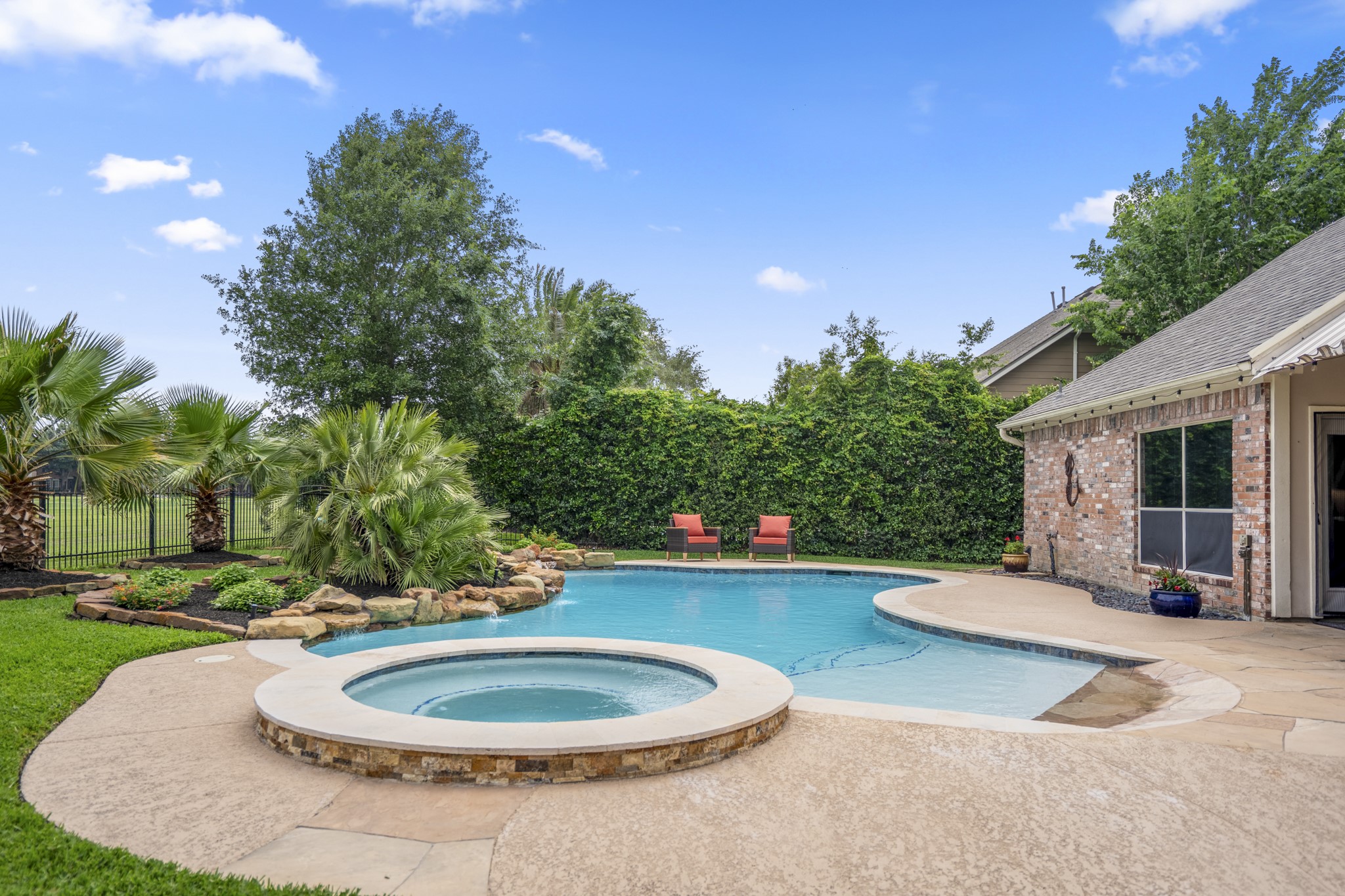 5835 Pinelake Crossing Drive Spring, TX 77379 - Photo 34 of 50 From this angle, the pool and spa take center stage, with the beach entry, natural stone accents, and surrounding landscaping all coming into focus. Recent improvements—including pool resurfacing with new plaster, updated decking and coping, refreshed tile, and upgraded lighting—add both beauty and peace of mind. Beyond the fence, open golf course views continue to carry through the space.