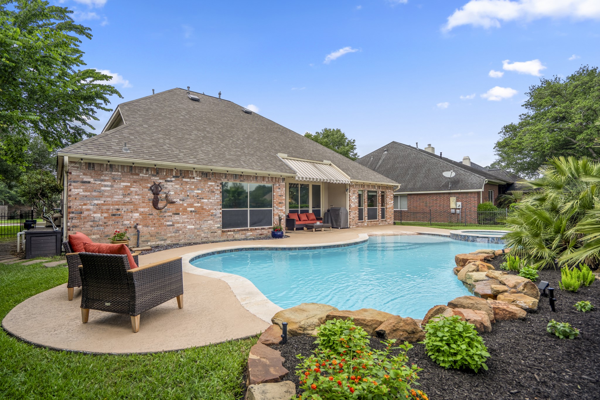 5835 Pinelake Crossing Drive Spring, TX 77379 - Photo 36 of 50 A different angle around the pool highlights the natural stone accents, lush landscaping, and the way the water curves through the space. With multiple spots to sit and unwind, it’s easy to take in the setting—especially with those open golf course views just beyond the rear fence behind us.