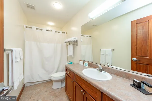 a bathroom with a granite countertop sink a toilet a mirror and shower