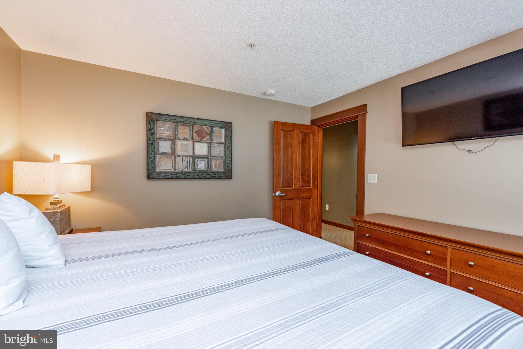 565 Glendale Road, Unit 106B Oakland, MD 21550 - Photo 15 of 27 a bedroom with a large bed and a tv