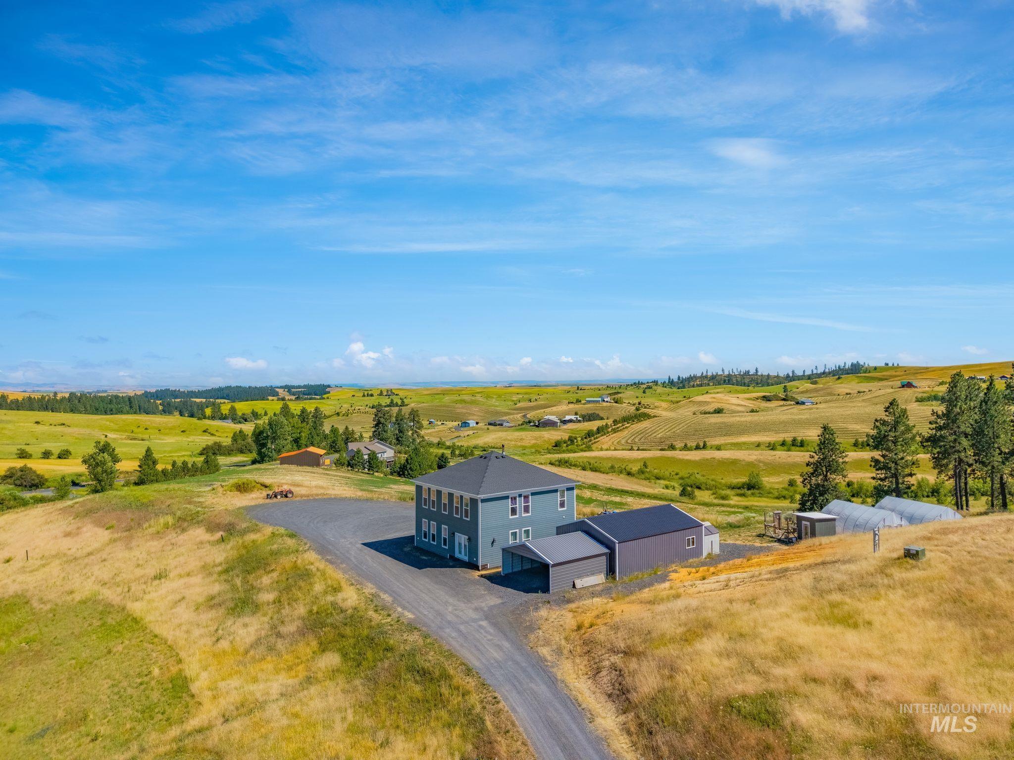 4935 Lenville Road Moscow, ID 83843 - Photo 1 of 49 Two-story residence with a gray exterior, complemented by an attached carport and a detached accessory structure