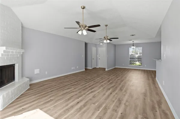 a view of an empty room with window and wooden floor