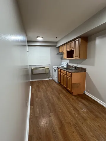 a kitchen with stainless steel appliances wooden floor and a refrigerator
