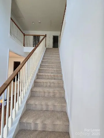 a view of staircase with wooden floor and white walls