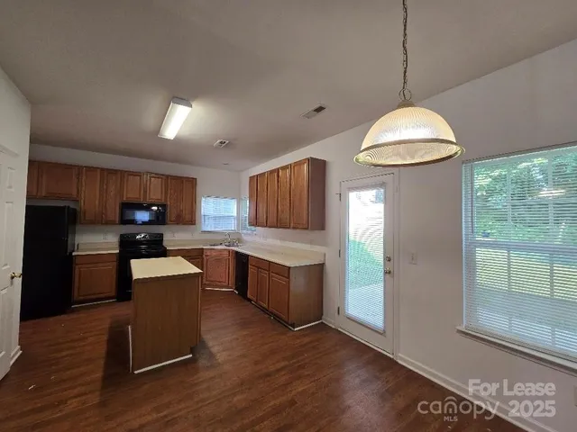 a kitchen with granite countertop a stove a sink a refrigerator and a wooden floor