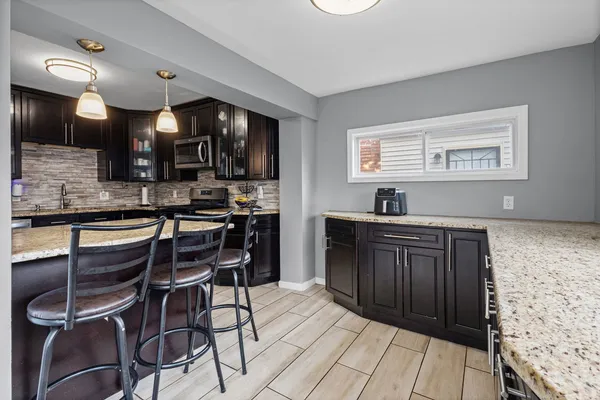 a kitchen with stainless steel appliances kitchen island granite countertop a stove a sink a dining table and chairs