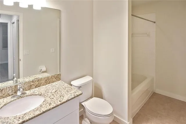 a bathroom with a granite countertop sink a toilet a mirror and shower