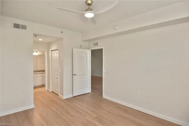 an empty room with wooden floor and ceiling fan