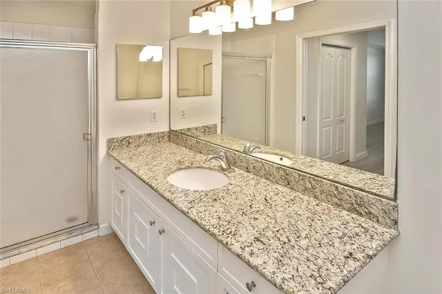 a bathroom with a granite countertop sink and a mirror
