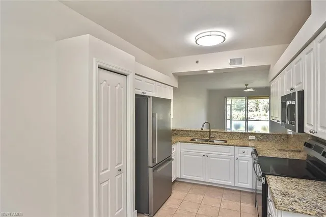 a large white kitchen with a sink and dishwasher a refrigerator with white cabinets