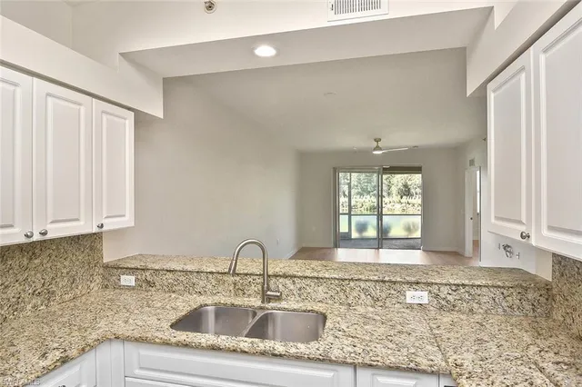 a kitchen with granite countertop a sink window and cabinets
