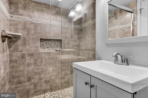 a bathroom with a sink shower and a mirror
