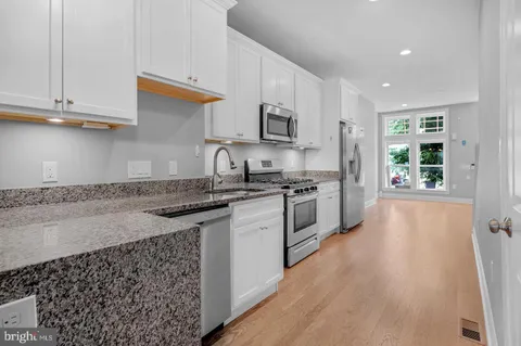 a kitchen with stainless steel appliances granite countertop a stove a sink and a refrigerator