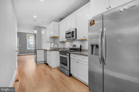 a kitchen with stainless steel appliances granite countertop a refrigerator a stove and a sink