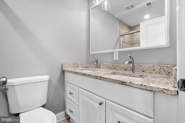 a bathroom with a granite countertop toilet sink and mirror