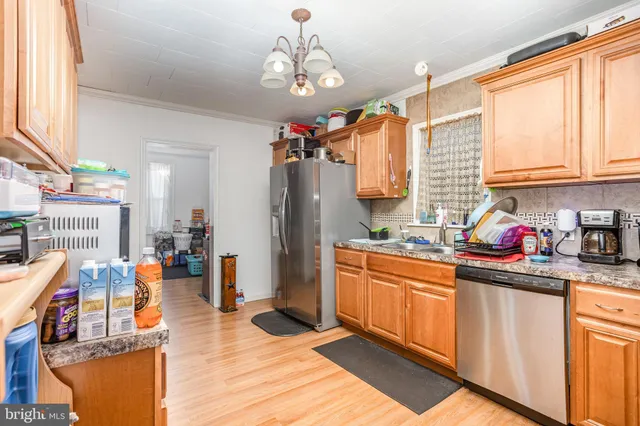 a kitchen with stainless steel appliances granite countertop a refrigerator a sink dishwasher and a dining table with wooden floor