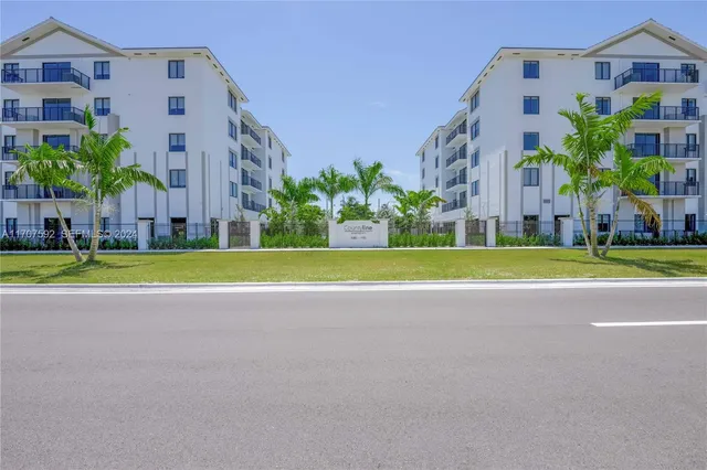a view of a tall building next to a big yard and large trees