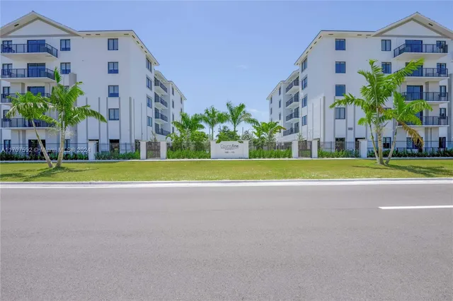 a view of a tall building next to a big yard and large trees