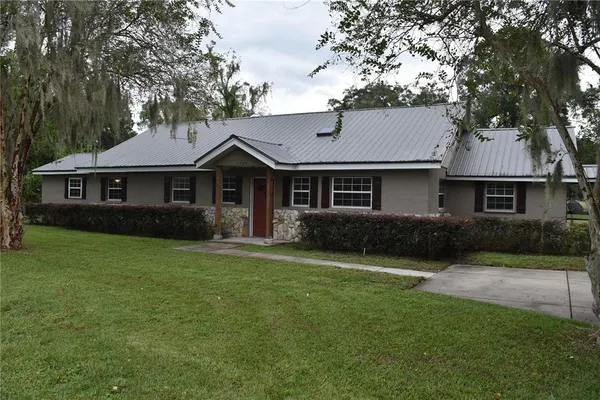 a front view of a house with a garden and trees