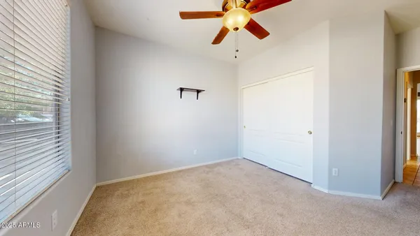 an empty room with a chandelier fan and a window