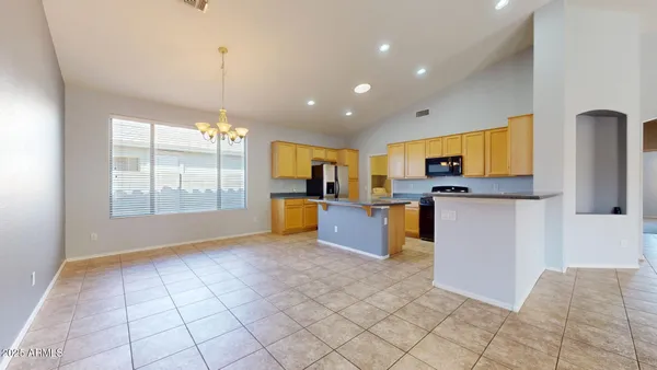 a kitchen with stainless steel appliances kitchen island granite countertop a refrigerator a stove top oven a sink a dining table and chairs with wooden floor