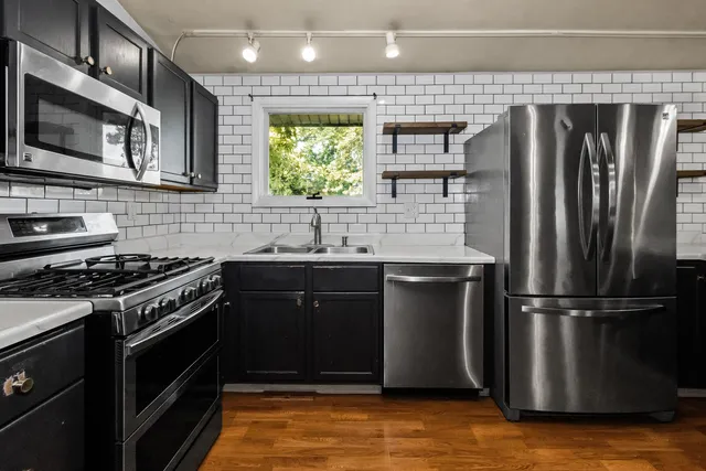 a kitchen with stainless steel appliances granite countertop a refrigerator and a stove