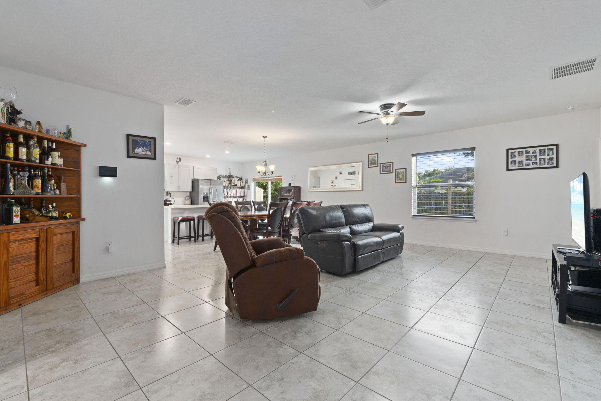 1414 Southwest Crest Avenue Port St. Lucie, FL 34953 - Photo 11 of 41 a living room with furniture a flat screen tv and a refrigerator