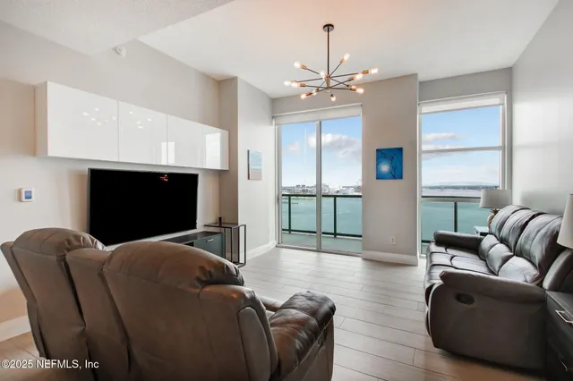 a living room with furniture a chandelier and a flat screen tv