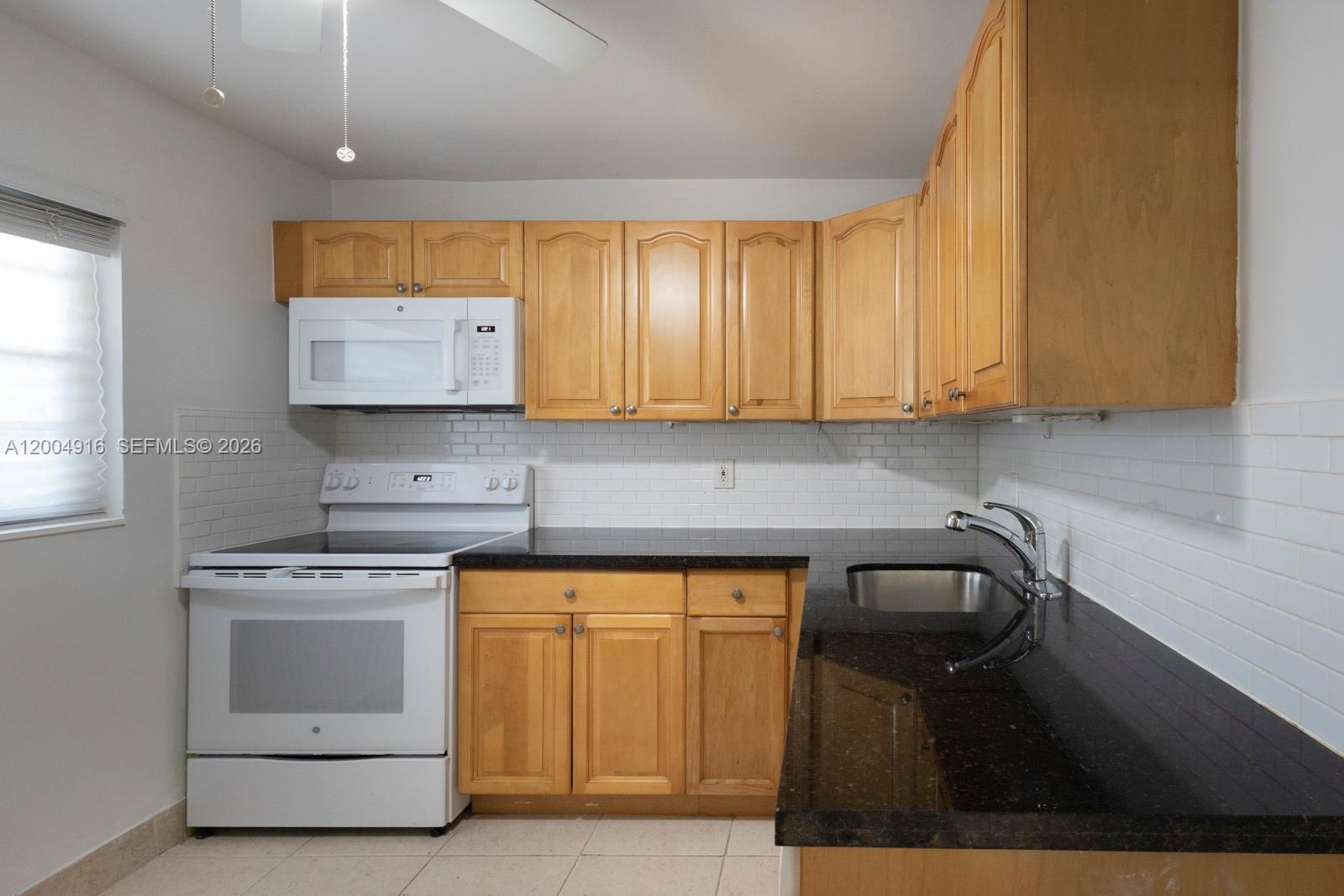 7747 Southwest 86th Street, Unit D205 Miami, FL 33143 - Photo 11 of 15 a kitchen with a sink a stove and cabinets