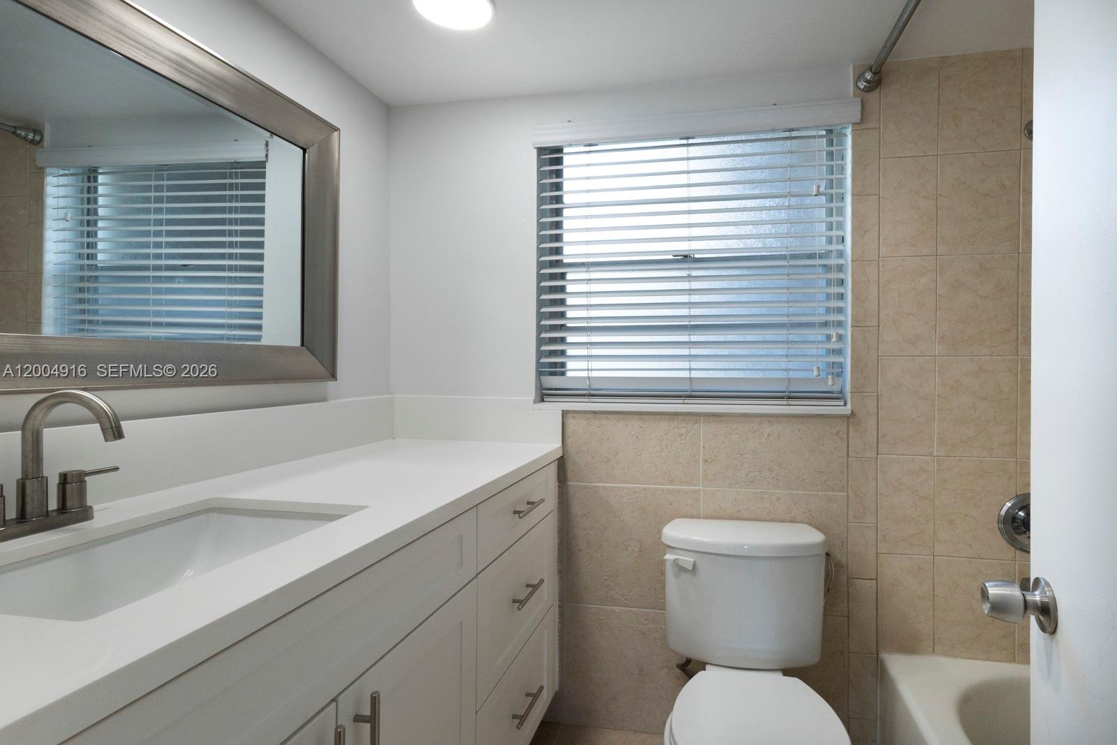 7747 Southwest 86th Street, Unit D205 Miami, FL 33143 - Photo 15 of 15 a bathroom with a toilet sink and window