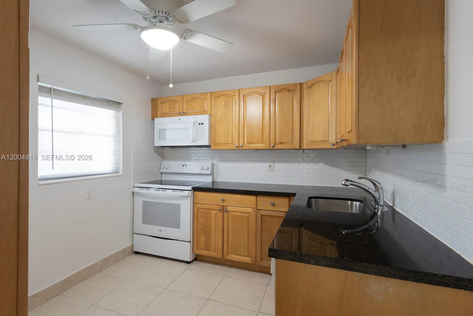 7747 Southwest 86th Street, Unit D205 Miami, FL 33143 - Photo 9 of 15 a kitchen with a sink stove and cabinets