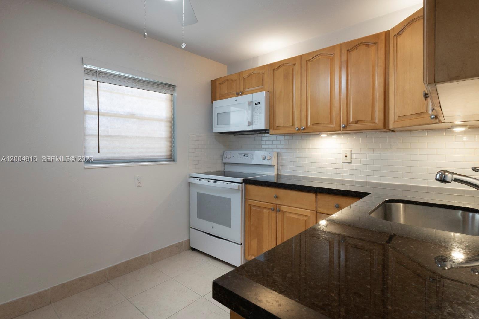 7747 Southwest 86th Street, Unit D205 Miami, FL 33143 - Photo 10 of 15 a kitchen with granite countertop a sink a stove and cabinets